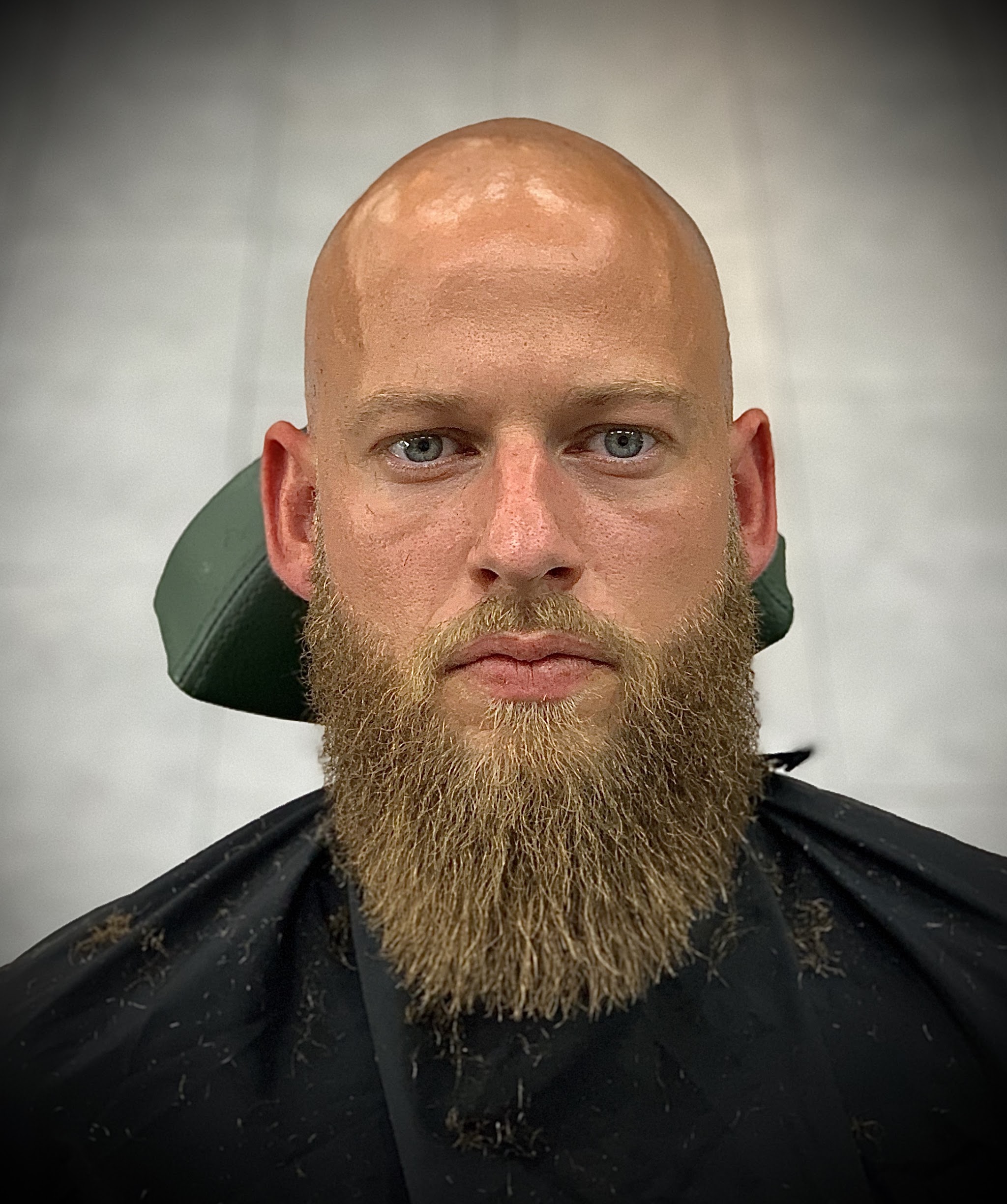 Volle baard, strak bijgewerkt, klant recht in de camera